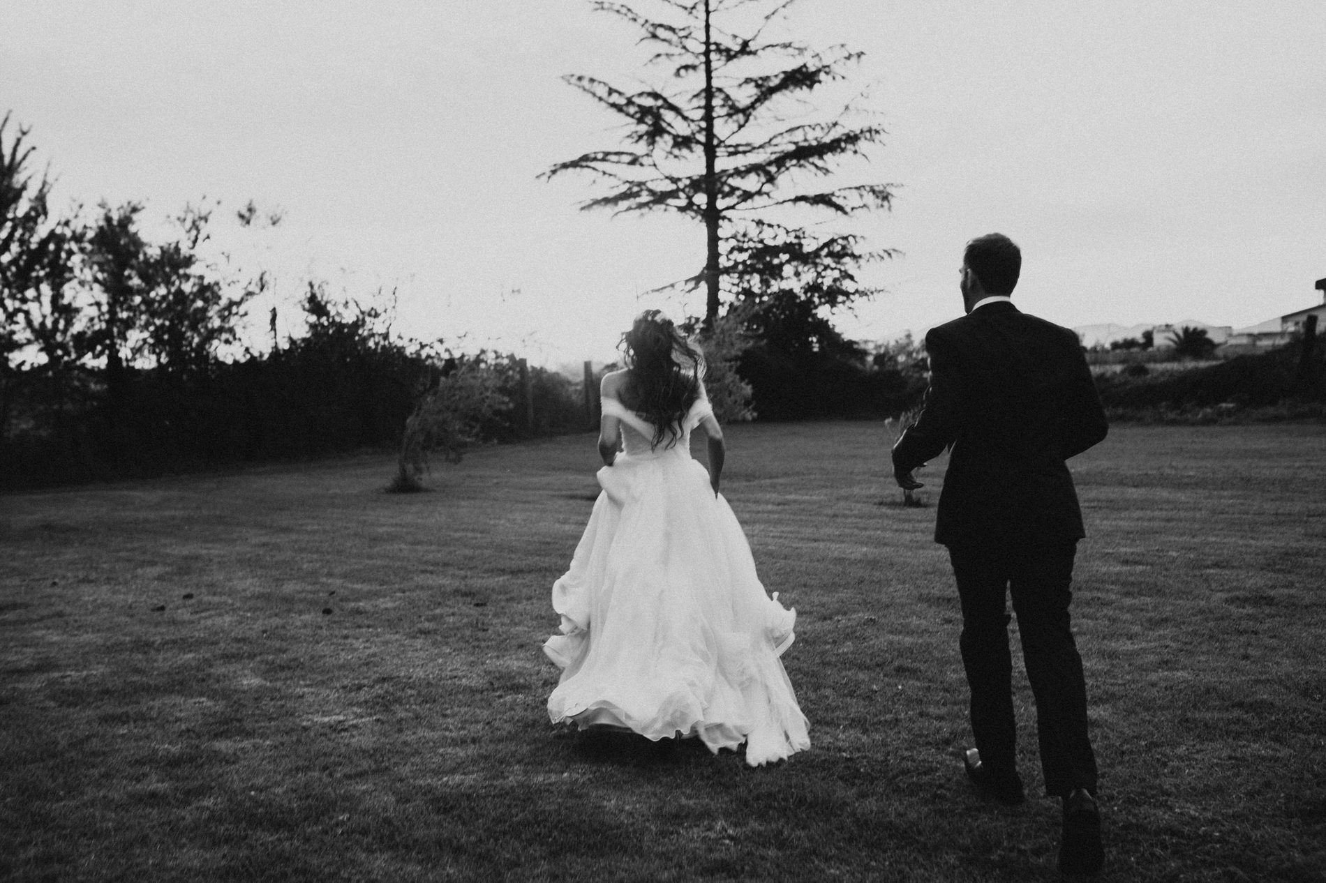 Bride and groom running across a lawn together